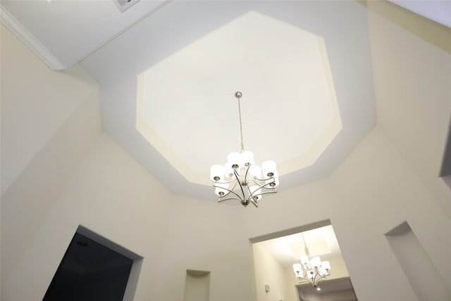 details with a tray ceiling, crown molding, and a chandelier