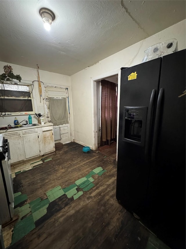 kitchen featuring black refrigerator with ice dispenser, dark wood-type flooring, a textured ceiling, and stove