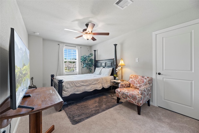 bedroom featuring a textured ceiling, light colored carpet, and ceiling fan