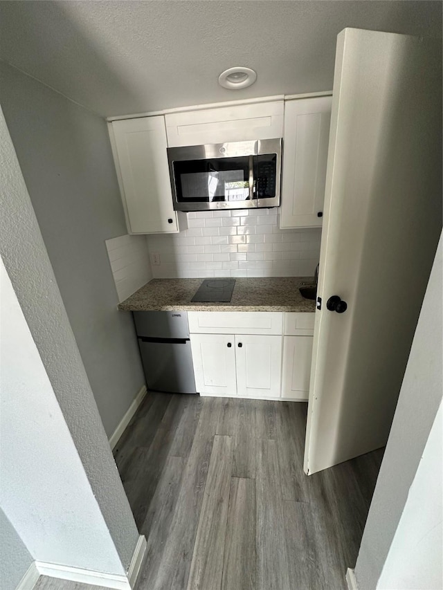 kitchen featuring dark hardwood / wood-style flooring, backsplash, white cabinetry, dark stone countertops, and black electric cooktop