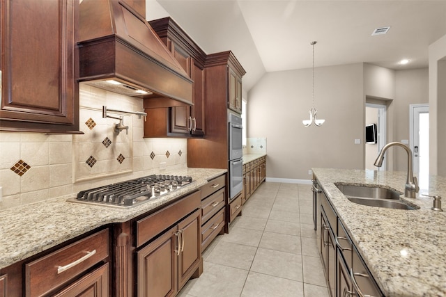 kitchen featuring sink, custom exhaust hood, decorative light fixtures, light stone counters, and stainless steel appliances