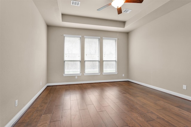 unfurnished room with ceiling fan, dark wood-type flooring, and a tray ceiling