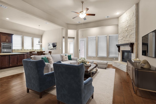 living room featuring ceiling fan, light hardwood / wood-style flooring, and a fireplace