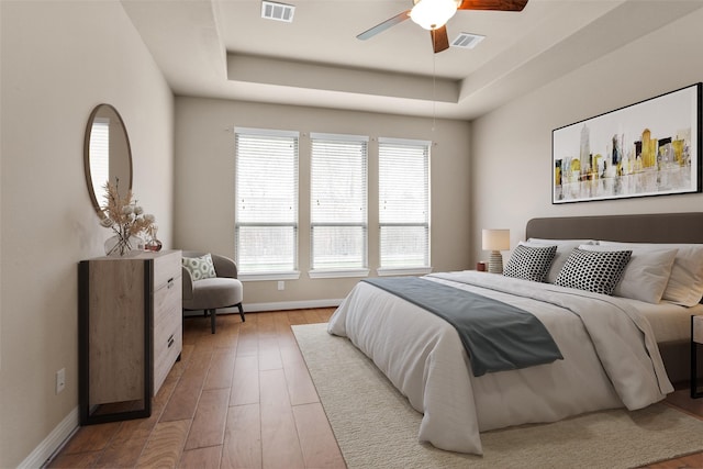 bedroom featuring ceiling fan, hardwood / wood-style flooring, and a tray ceiling