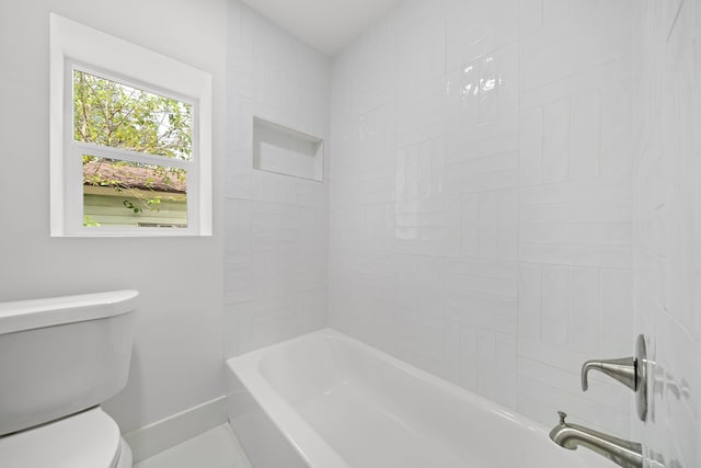 bathroom featuring toilet and tiled shower / bath