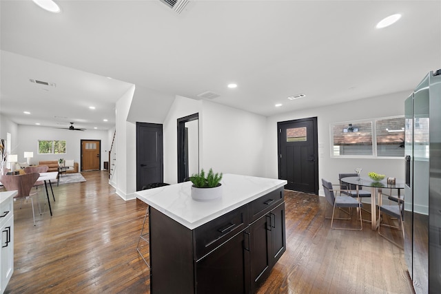 kitchen with a center island, a kitchen bar, dark hardwood / wood-style flooring, ceiling fan, and dark brown cabinets