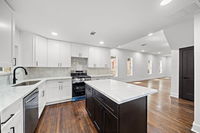 kitchen with sink, a kitchen island, white cabinets, stainless steel appliances, and dark hardwood / wood-style floors