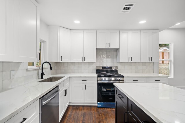 kitchen featuring appliances with stainless steel finishes, tasteful backsplash, white cabinetry, sink, and light stone counters