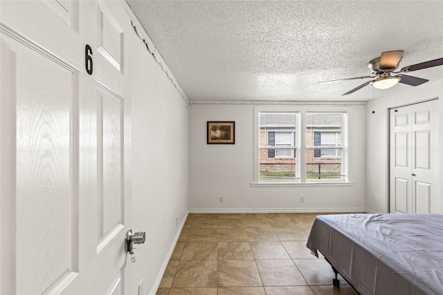 bedroom with ceiling fan, a textured ceiling, and baseboards