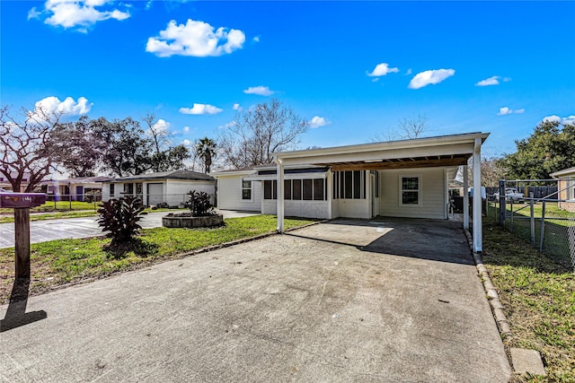 rear view of house with concrete driveway, a carport, and fence