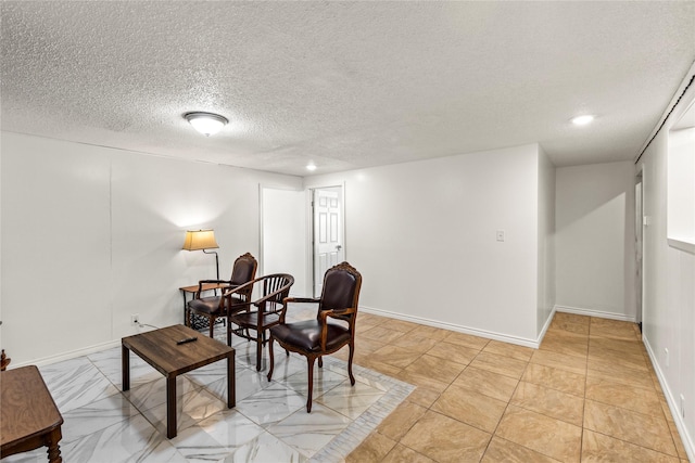 living area with a textured ceiling and baseboards