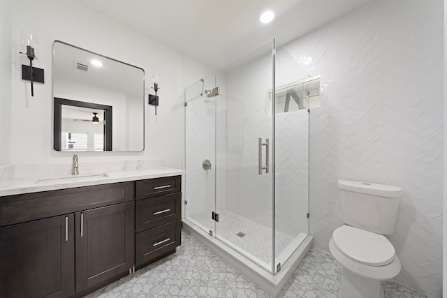 bathroom featuring toilet, a shower with shower door, and vanity