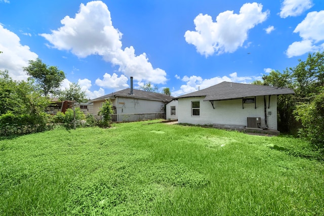 rear view of property featuring a yard and central AC