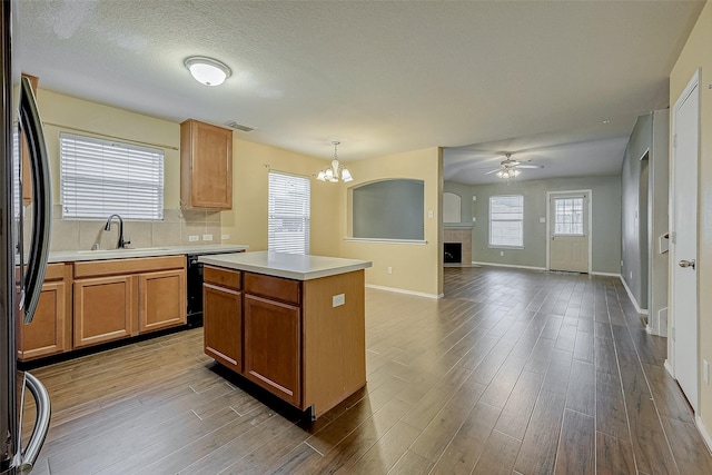 kitchen featuring sink, refrigerator, a center island, hanging light fixtures, and light wood-type flooring