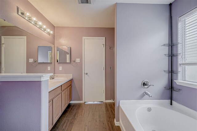 bathroom with vanity, a bath, and plenty of natural light