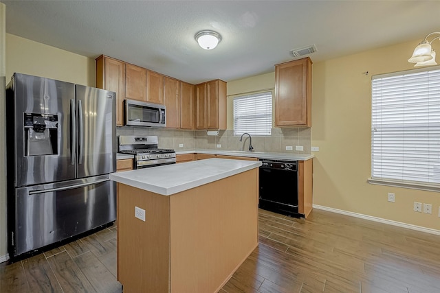 kitchen featuring tasteful backsplash, stainless steel appliances, hardwood / wood-style floors, and a kitchen island