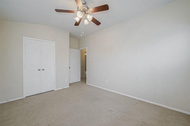 unfurnished bedroom featuring light carpet, lofted ceiling, a closet, and ceiling fan