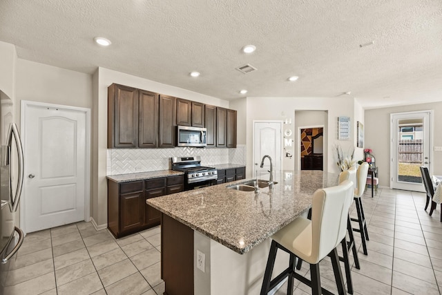 kitchen featuring light stone countertops, appliances with stainless steel finishes, sink, a breakfast bar, and a center island with sink