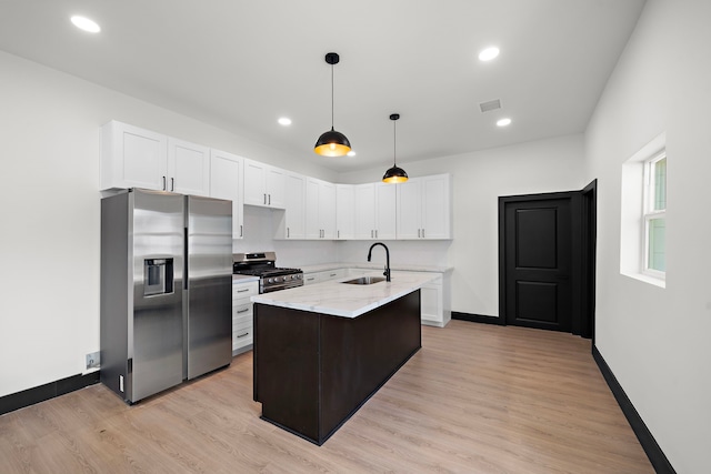 kitchen featuring sink, light stone counters, a kitchen island with sink, light hardwood / wood-style floors, and stainless steel appliances