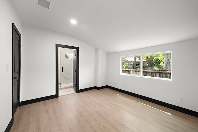 spare room featuring light hardwood / wood-style flooring and vaulted ceiling