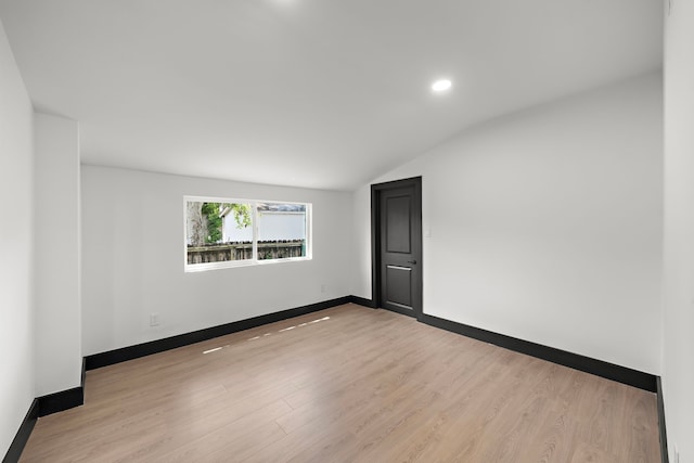 spare room with light hardwood / wood-style floors and lofted ceiling