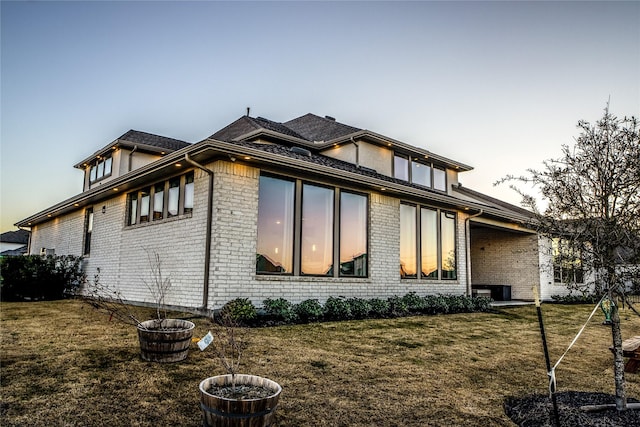 property exterior at dusk featuring a lawn