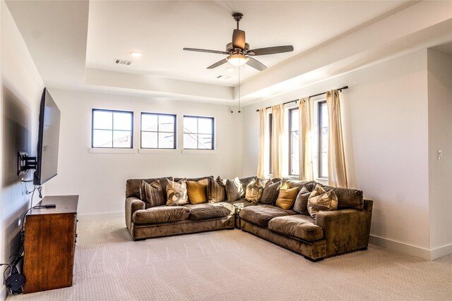 living room with ceiling fan, light carpet, and a raised ceiling