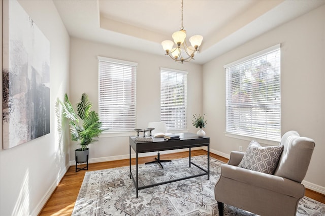 home office with hardwood / wood-style floors, a chandelier, and a tray ceiling