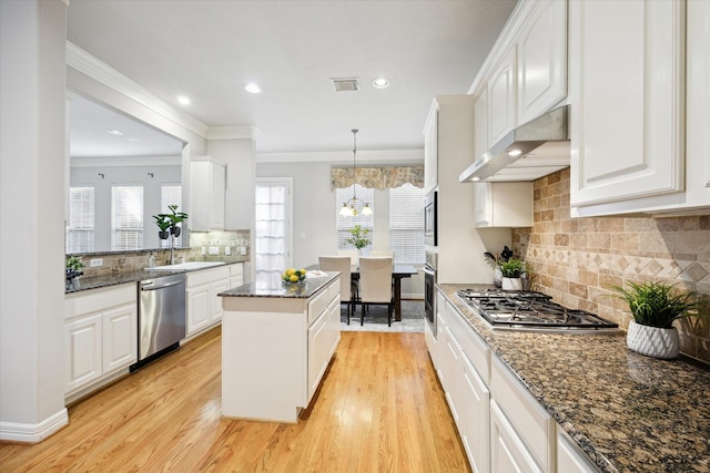 kitchen with ornamental molding, white cabinetry, a center island, and appliances with stainless steel finishes