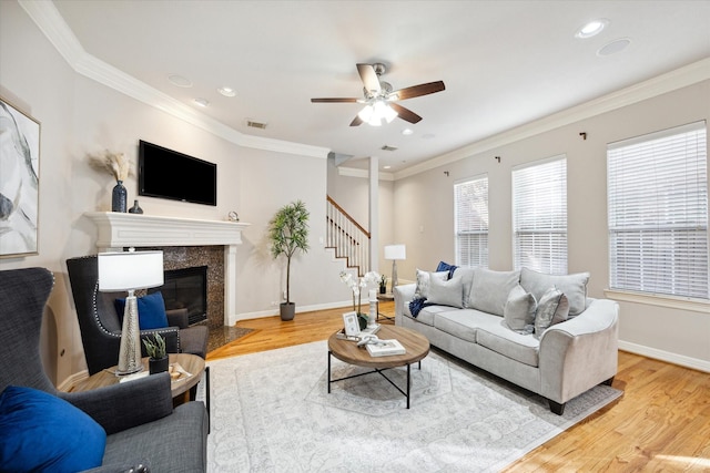 living room with ornamental molding, a premium fireplace, and hardwood / wood-style floors