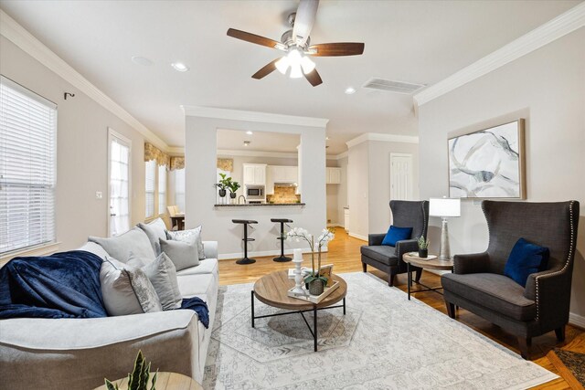 living room with hardwood / wood-style flooring, ceiling fan, and ornamental molding