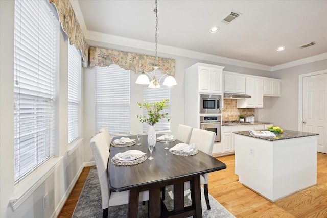 dining space with crown molding, light hardwood / wood-style floors, and a chandelier