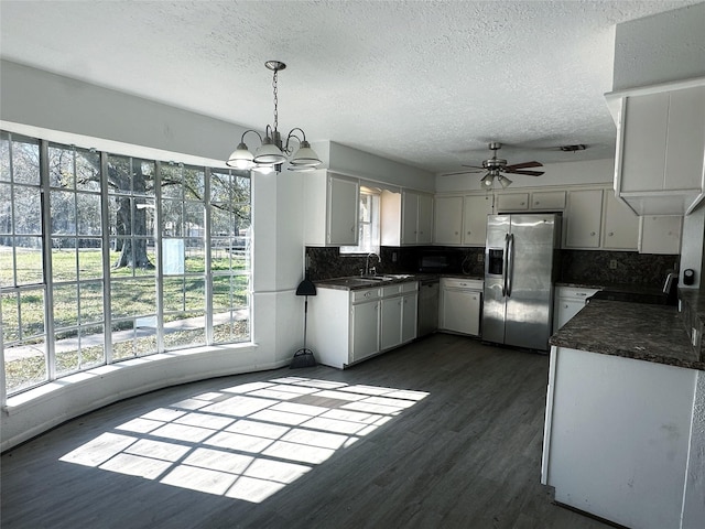 kitchen featuring pendant lighting, dark hardwood / wood-style flooring, appliances with stainless steel finishes, backsplash, and white cabinets