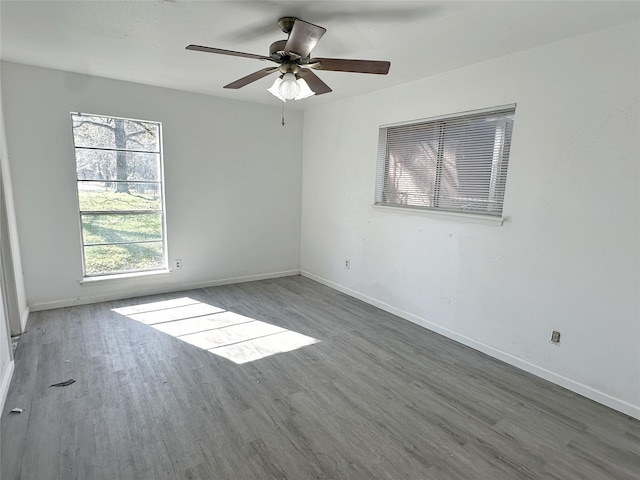 empty room featuring ceiling fan, dark wood-type flooring, and a wealth of natural light