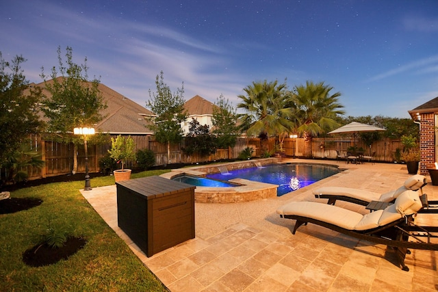 pool at dusk with an in ground hot tub and a patio area