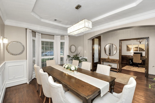 dining space featuring crown molding, a tray ceiling, dark hardwood / wood-style floors, and an inviting chandelier