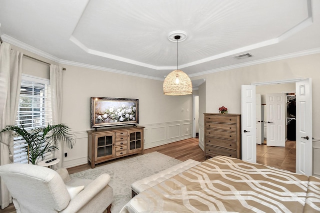 bedroom featuring hardwood / wood-style floors, ornamental molding, and a raised ceiling