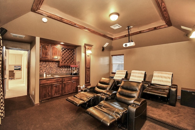 carpeted cinema with ornamental molding, bar area, and a tray ceiling