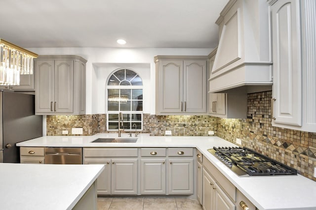 kitchen with tasteful backsplash, sink, gray cabinetry, stainless steel appliances, and custom range hood