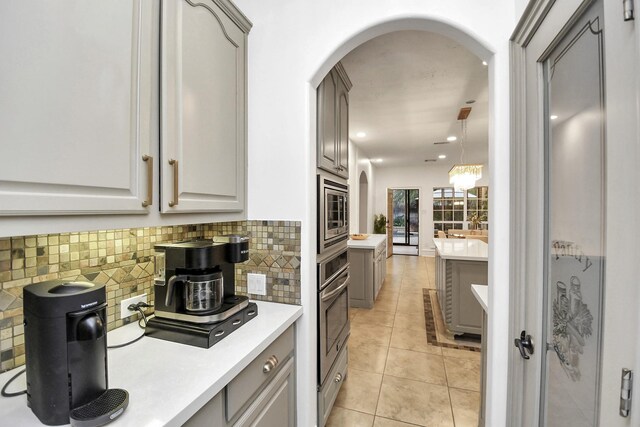 kitchen featuring gray cabinetry, light tile patterned floors, tasteful backsplash, and stainless steel appliances