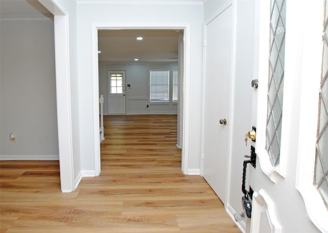 corridor with light hardwood / wood-style flooring and ornamental molding