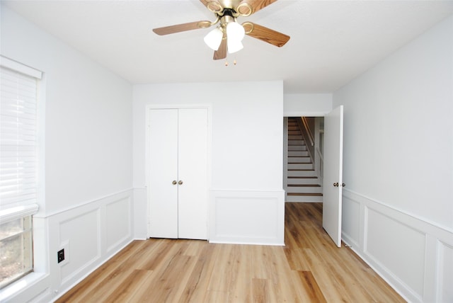 unfurnished bedroom featuring ceiling fan, a closet, and light wood-type flooring