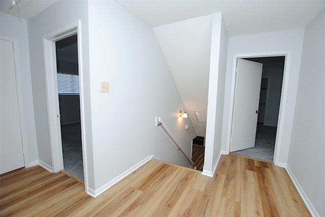 corridor featuring light hardwood / wood-style flooring and vaulted ceiling