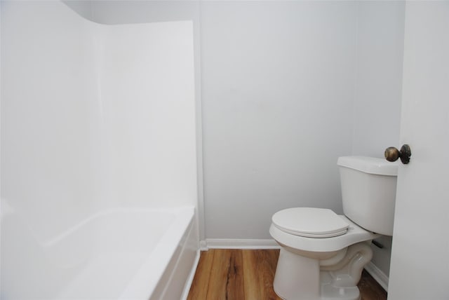 bathroom with a tub, hardwood / wood-style floors, and toilet