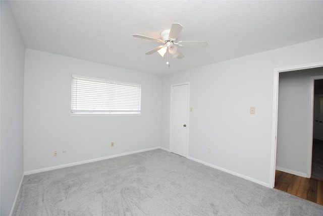 carpeted spare room featuring ceiling fan and a textured ceiling