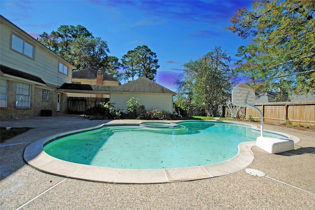 pool at dusk featuring an in ground hot tub and a patio area