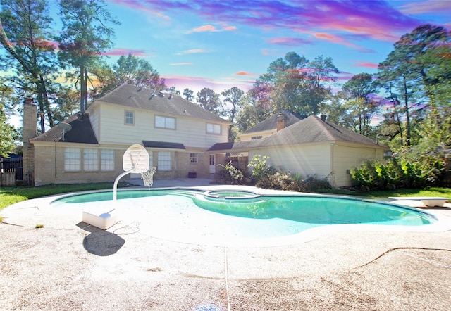 pool at dusk with an in ground hot tub