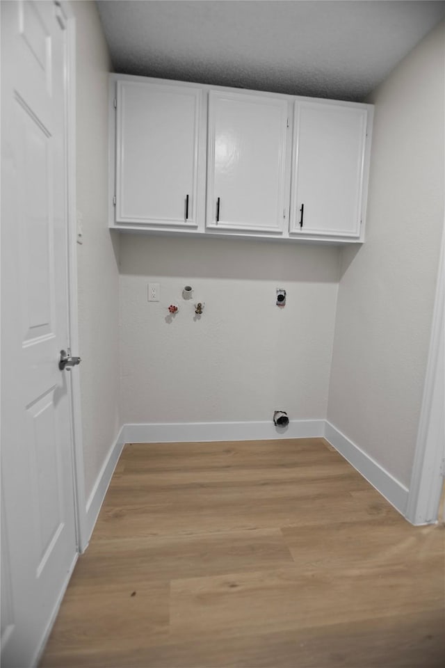 laundry room featuring cabinet space, electric dryer hookup, light wood-type flooring, and baseboards