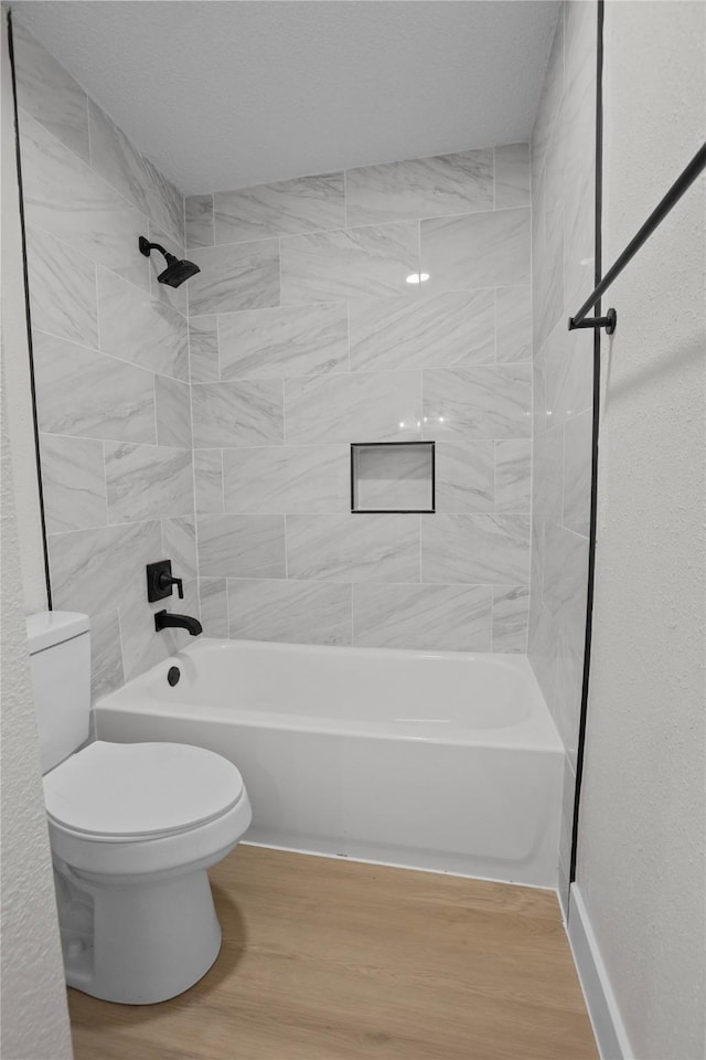 bathroom featuring toilet, bathing tub / shower combination, and wood finished floors