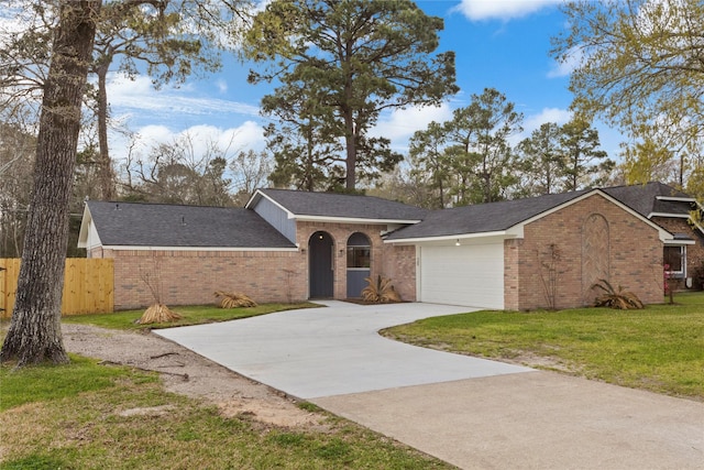 view of front of house with a front lawn, an attached garage, fence, and brick siding